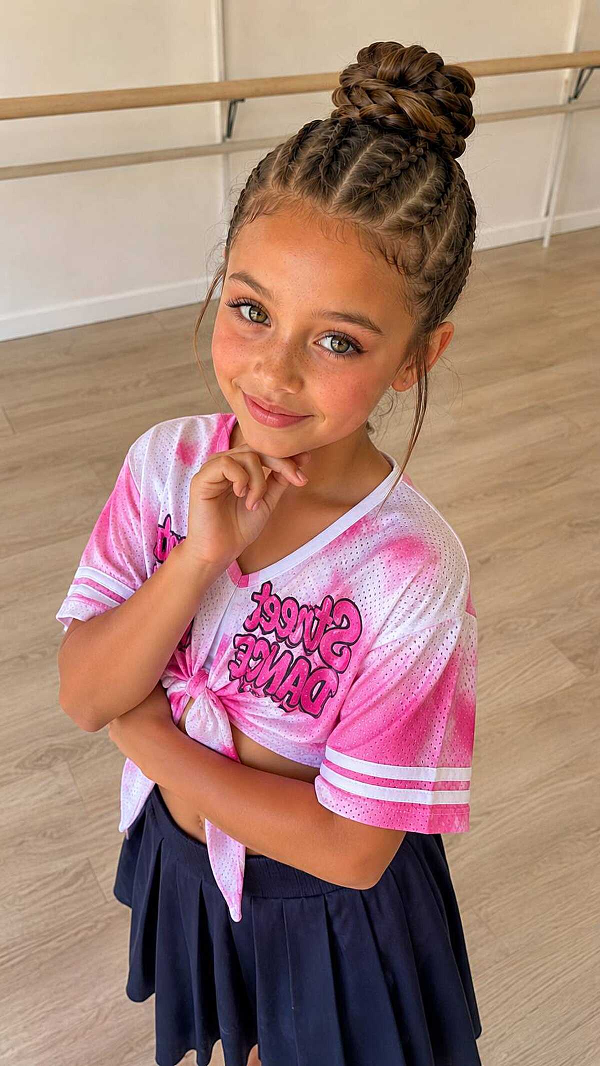Girl with two Dutch braids feeding into a top bun