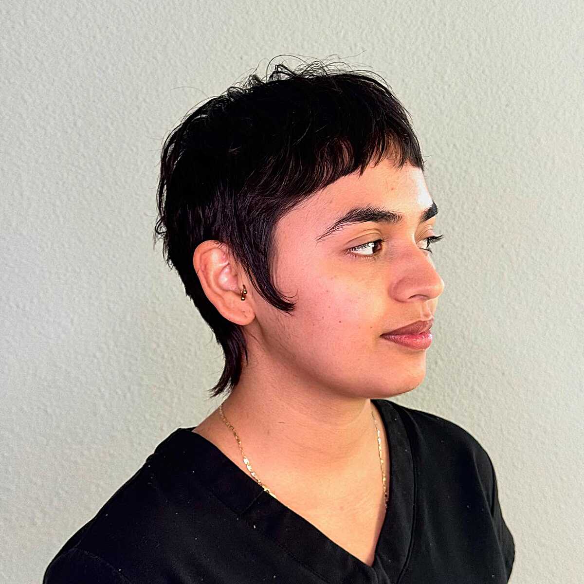 Choppy black pixie mullet with wispy fringe and sideburns