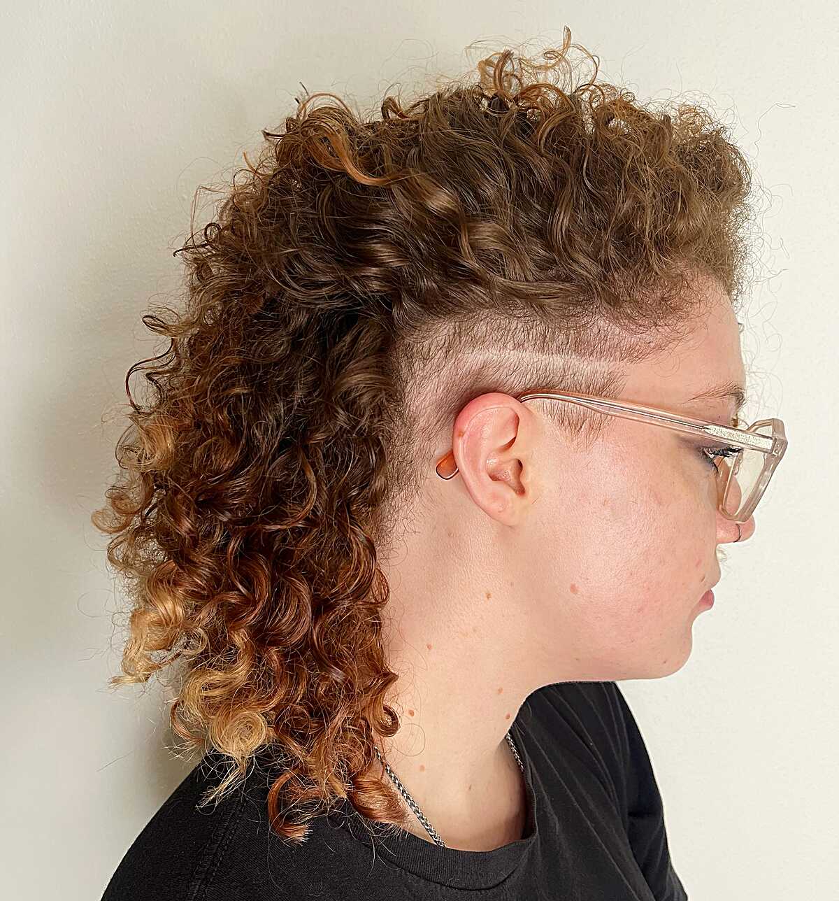 Curly brown mohawk with shaved sides and etched line detail
