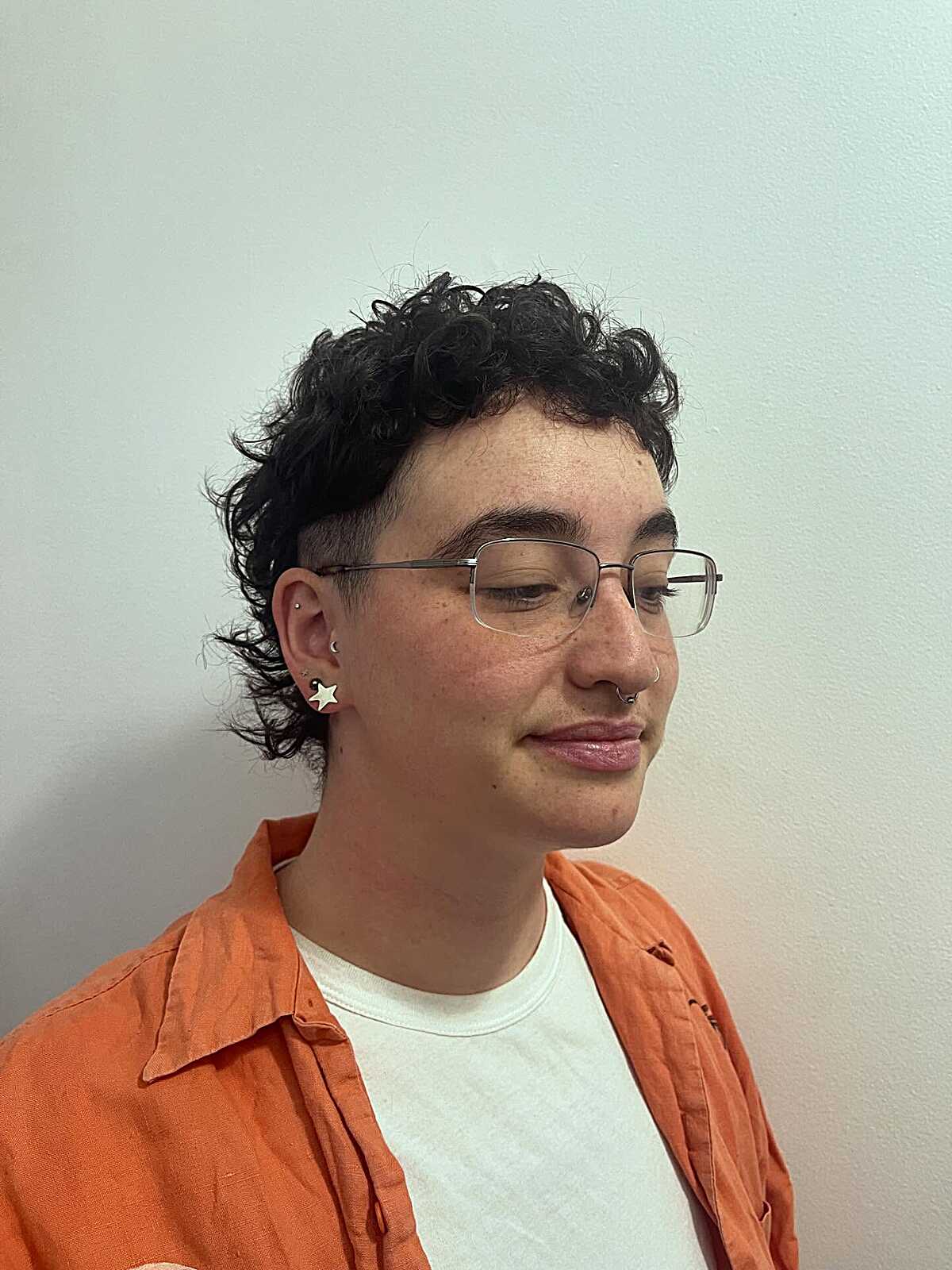 Black curly top with faded sides, glasses, and star earring