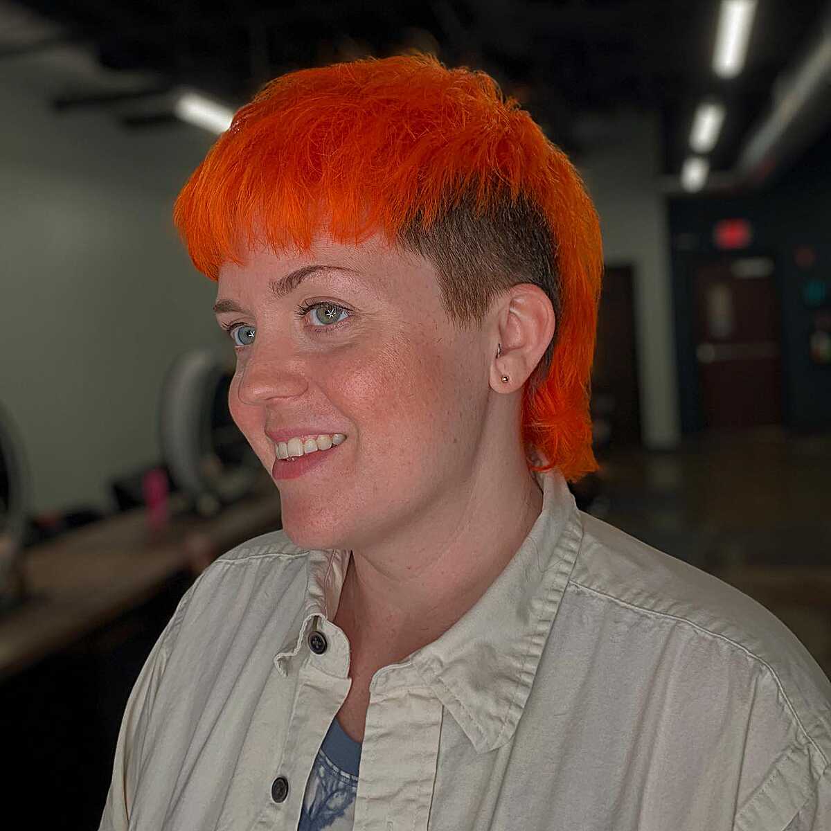 Bright neon orange shullet with buzzed sides and bangs