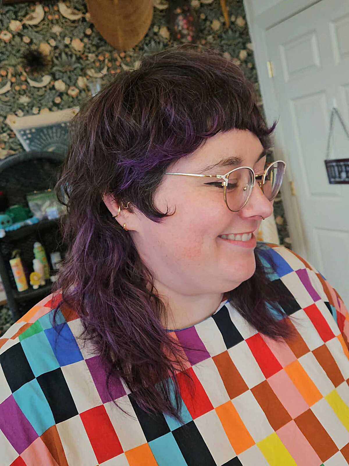 Dark wavy shag with purple tint, bangs, and glasses