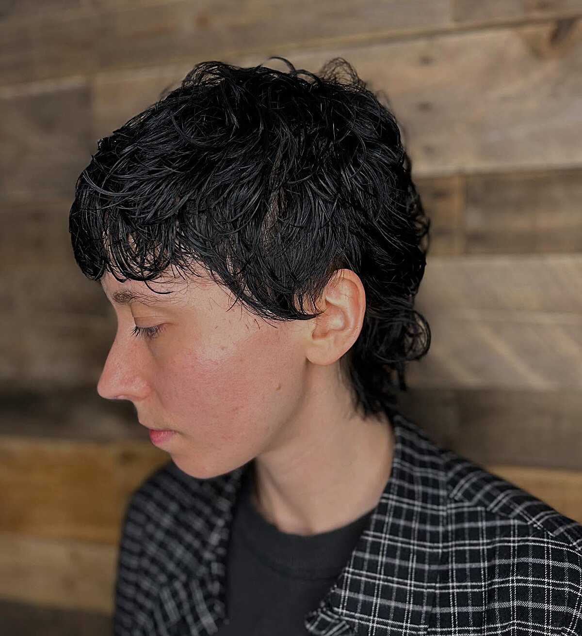 Black curly pixie mullet styled with a wet-look finish
