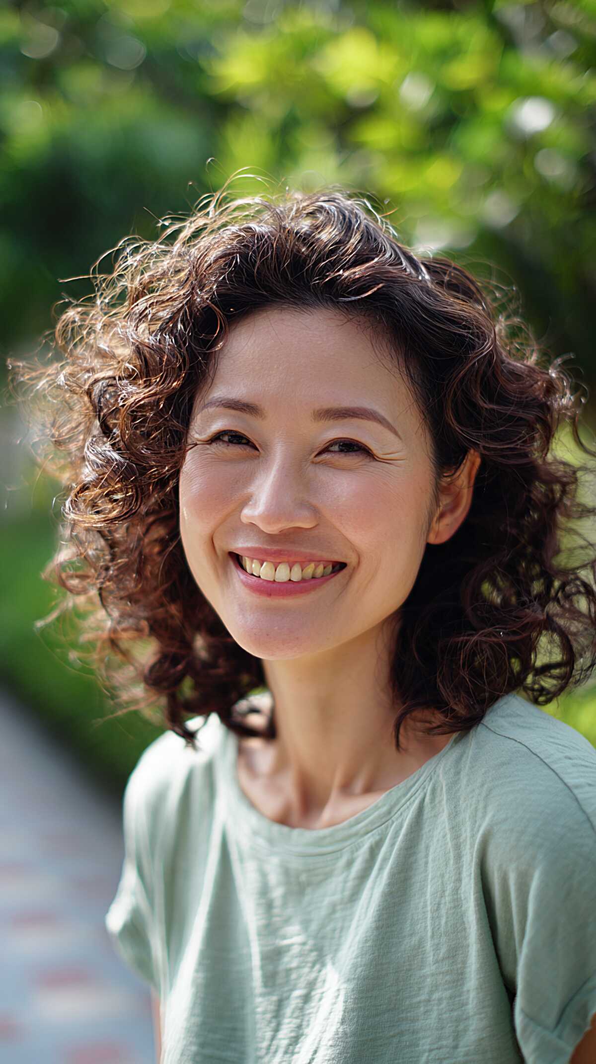 Shoulder-length dark curly perm with natural highlights
