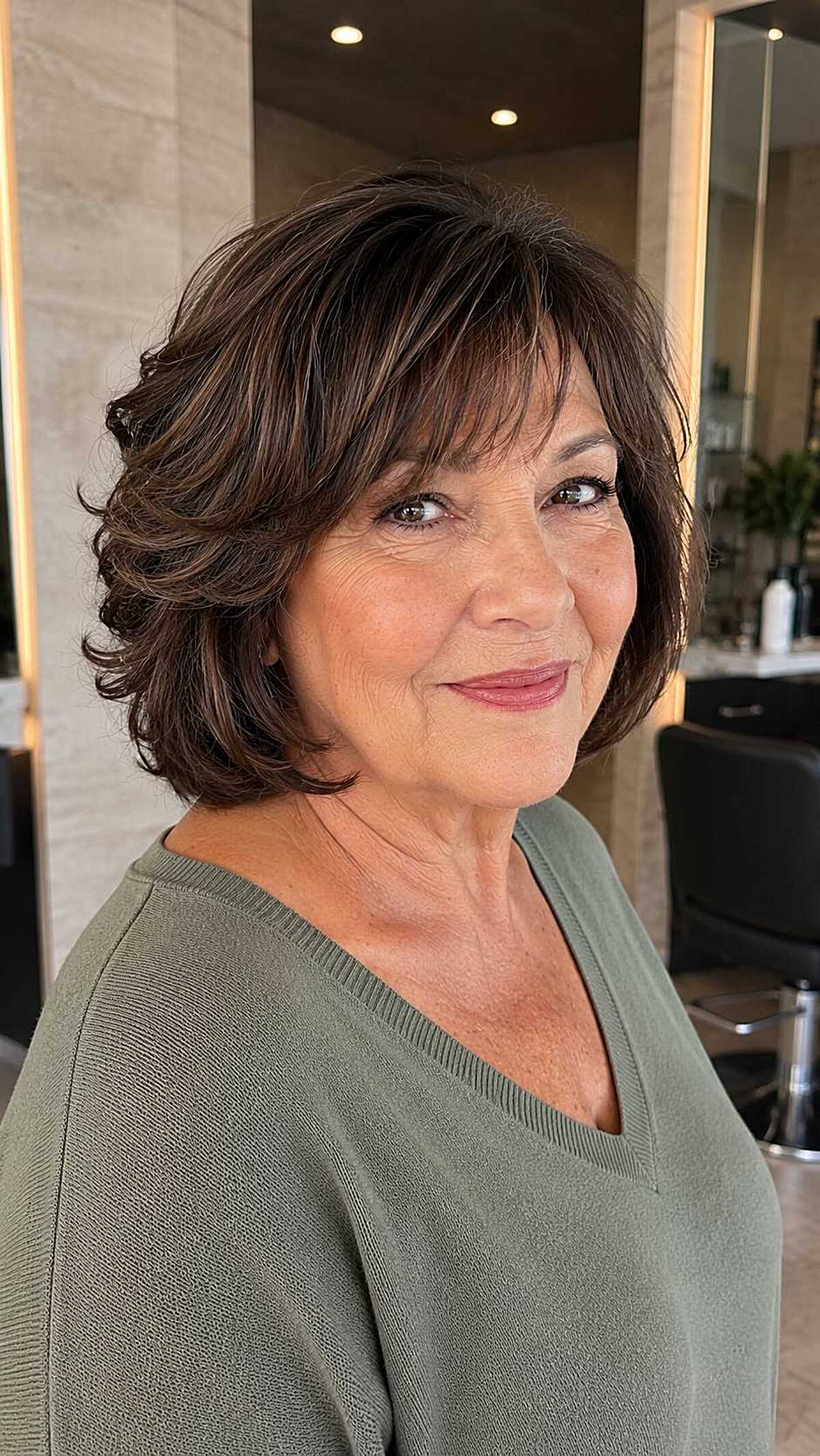 Layered brunette bob with feathered bangs on woman over 60