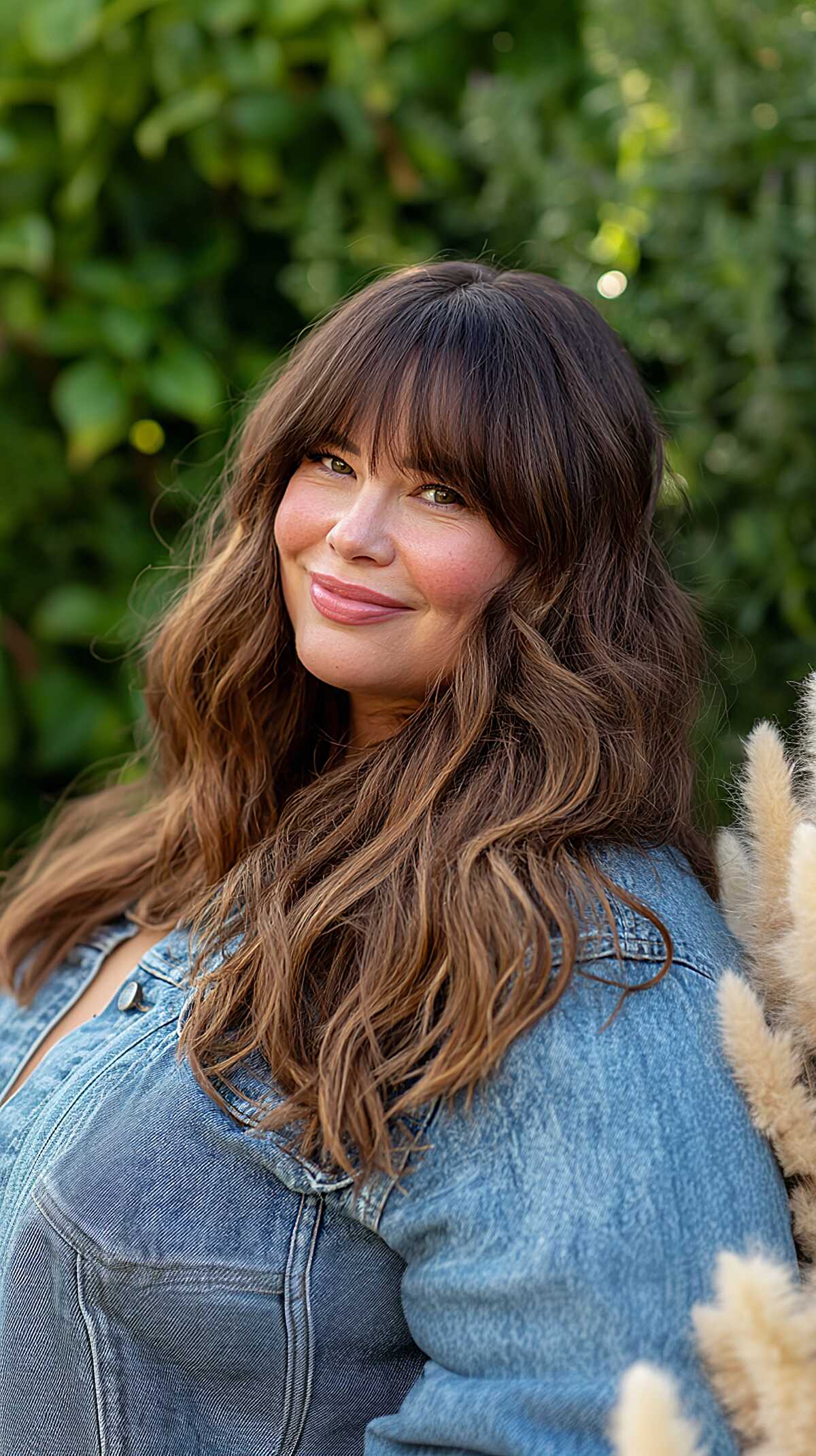 Long wavy brown hair with full bangs and caramel highlights