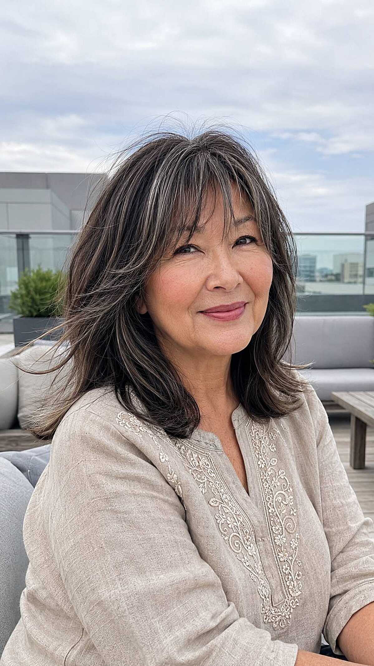Dark layered lob with long curtain bangs and gray streaks