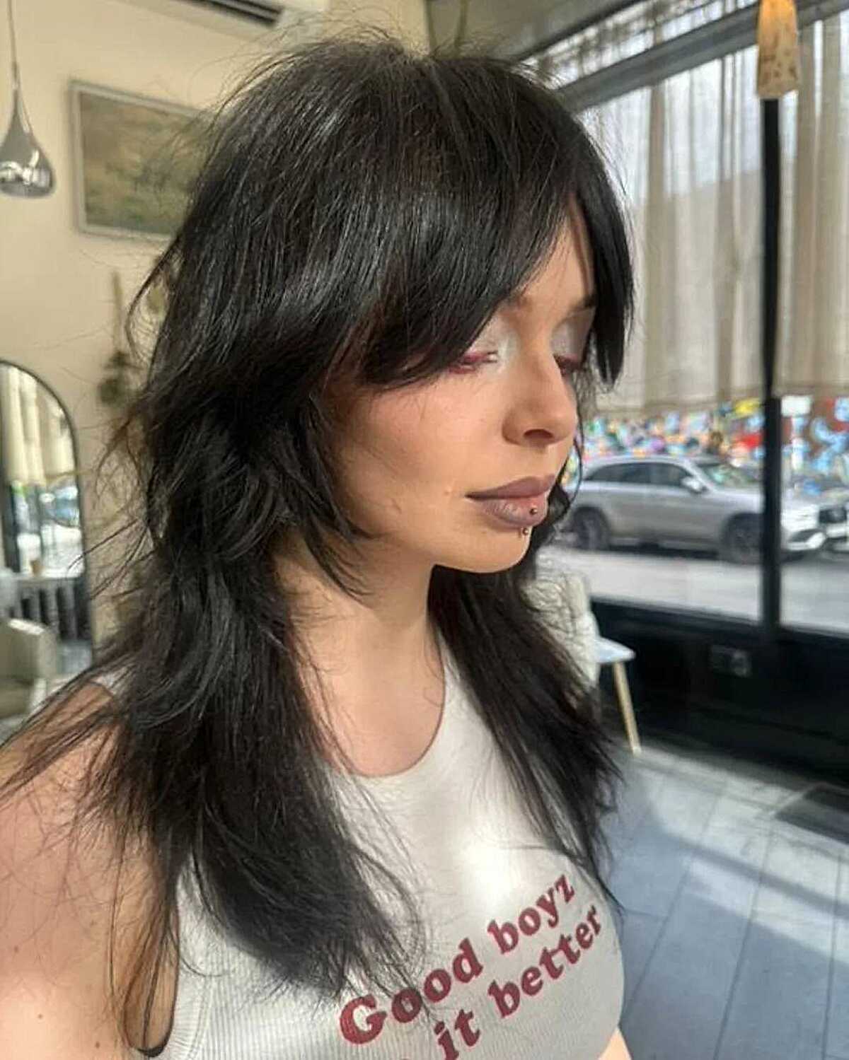 Long black razored wolf cut with heavy curtain bangs