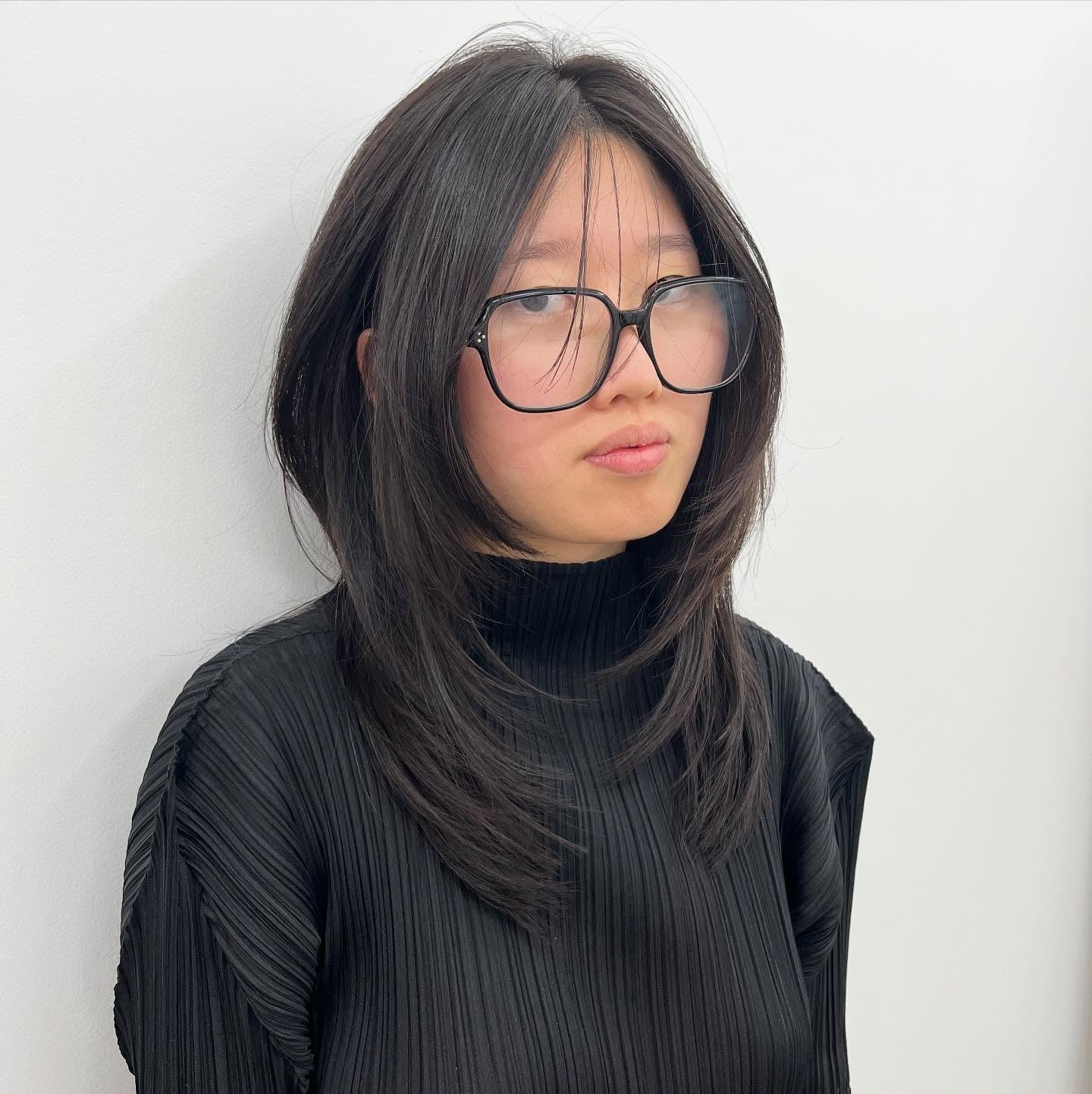 Straight dark wolf cut with long curtain bangs and glasses