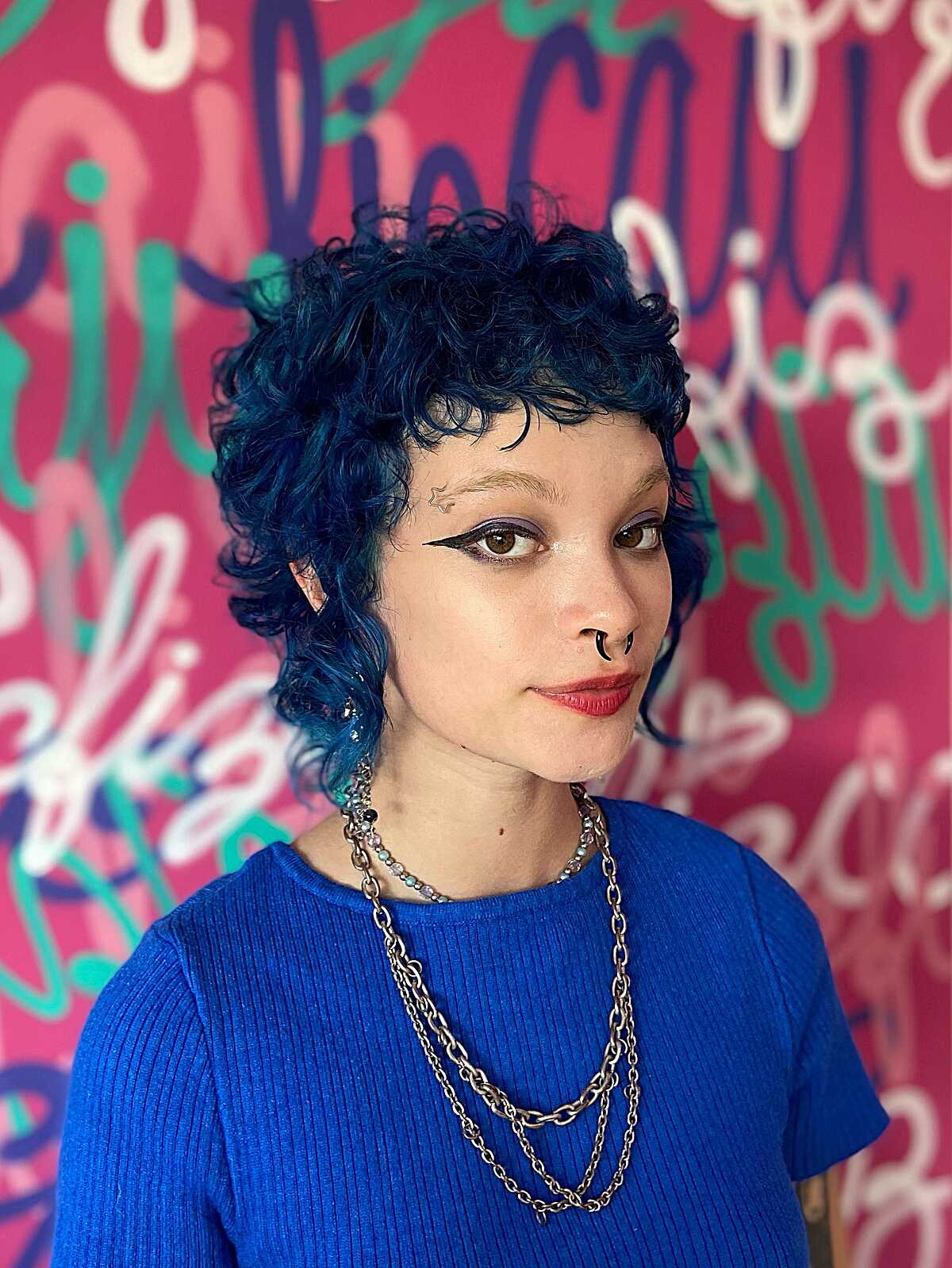 Curly blue-black mullet with tapered sides and bangs