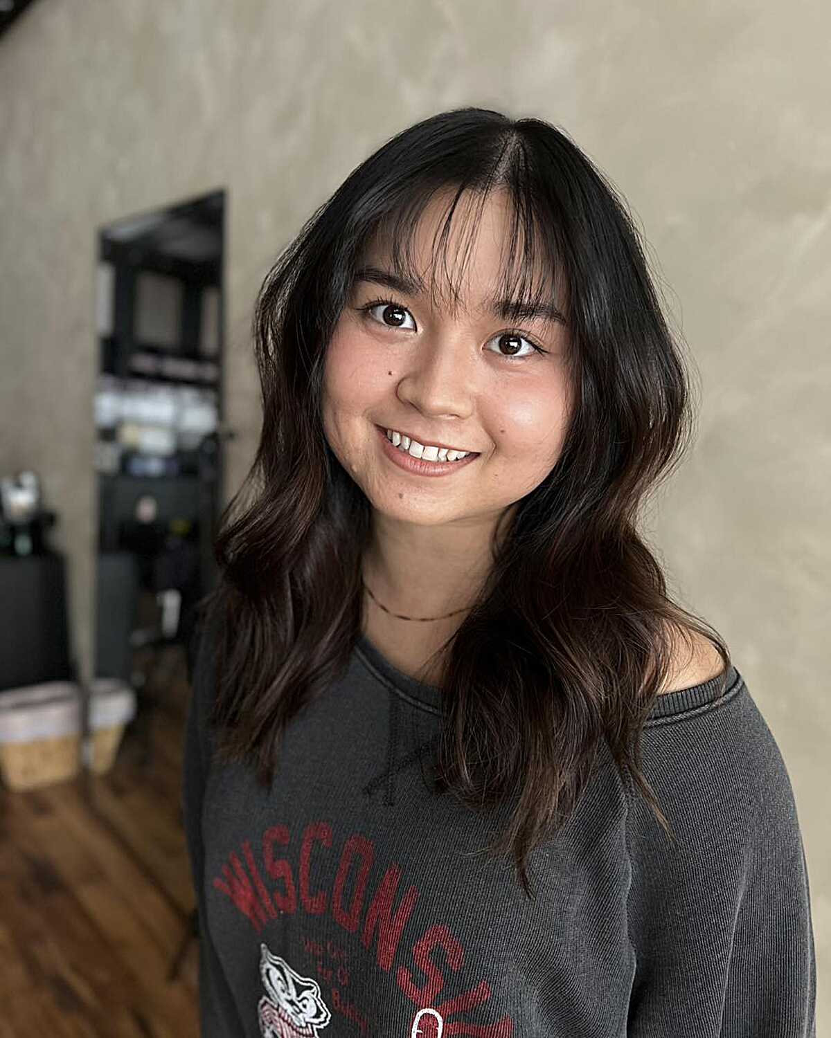 Medium dark wavy hair with soft curtain bangs