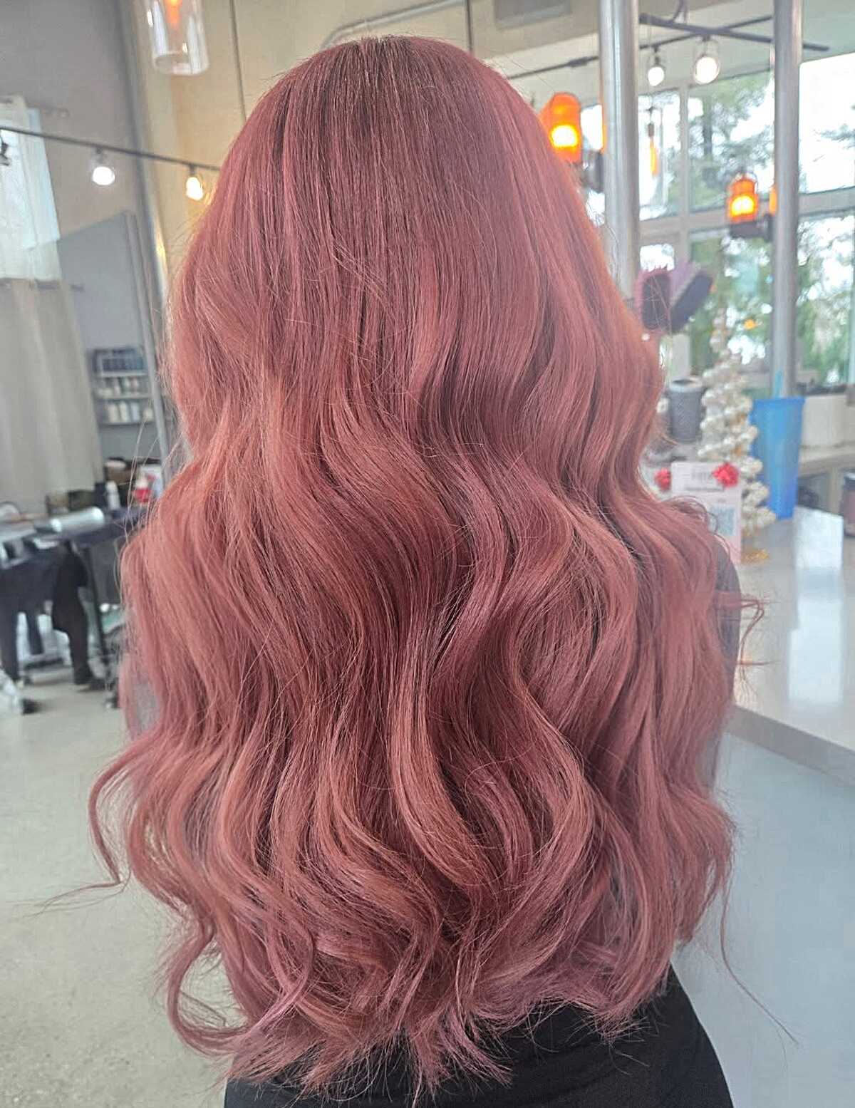 Long warm rosewood pink wavy hair in salon lighting