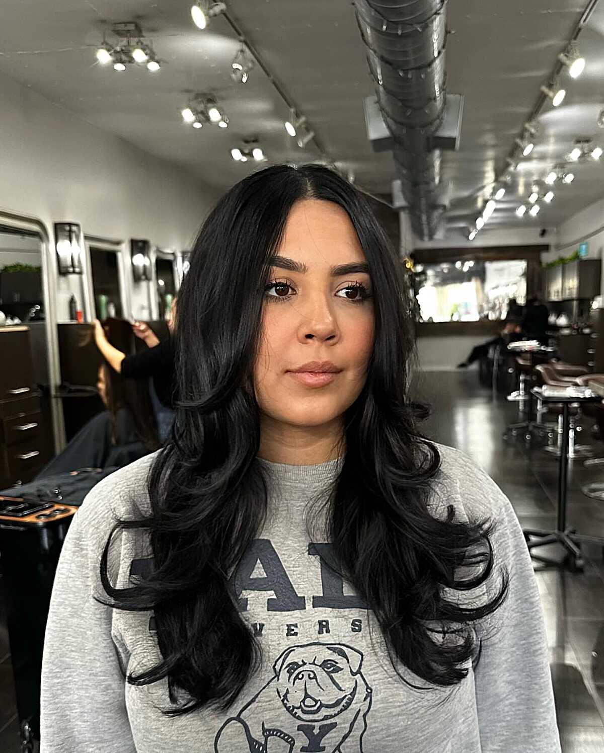 Black hair with bouncy curled layers and center part