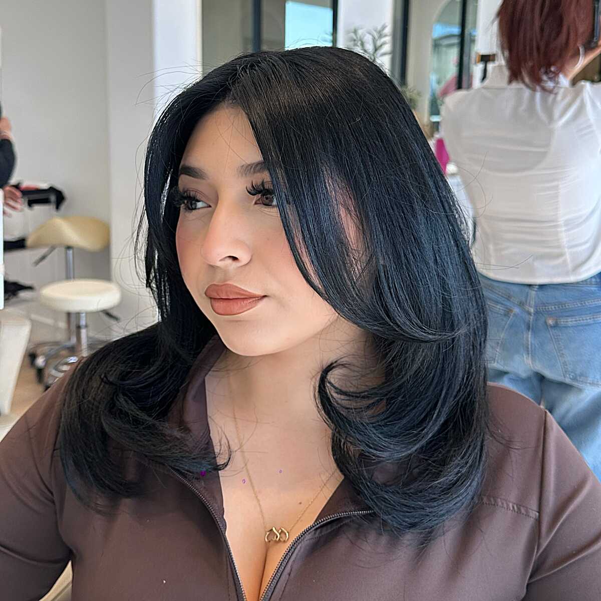 Glossy black medium length hair with styled face framing