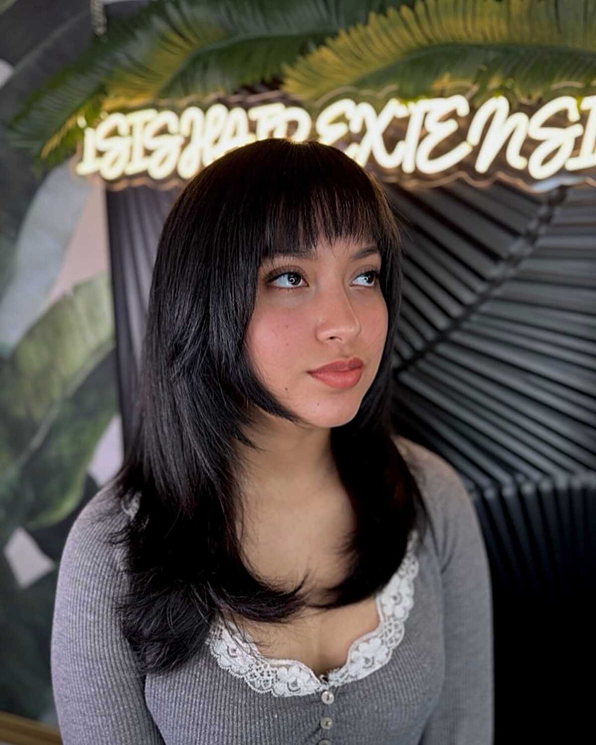 Black hair with straight across bangs and layered length