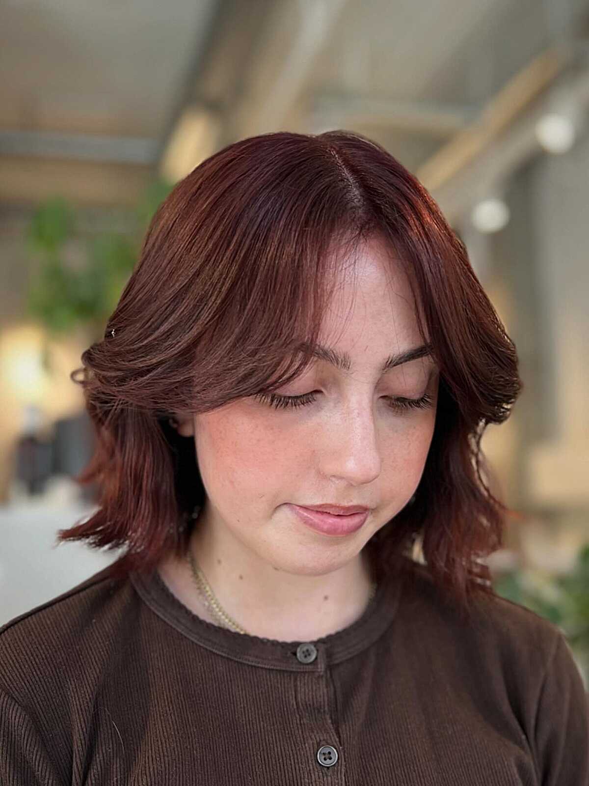 Rich burgundy cowgirl bob with curtain bangs and flip
