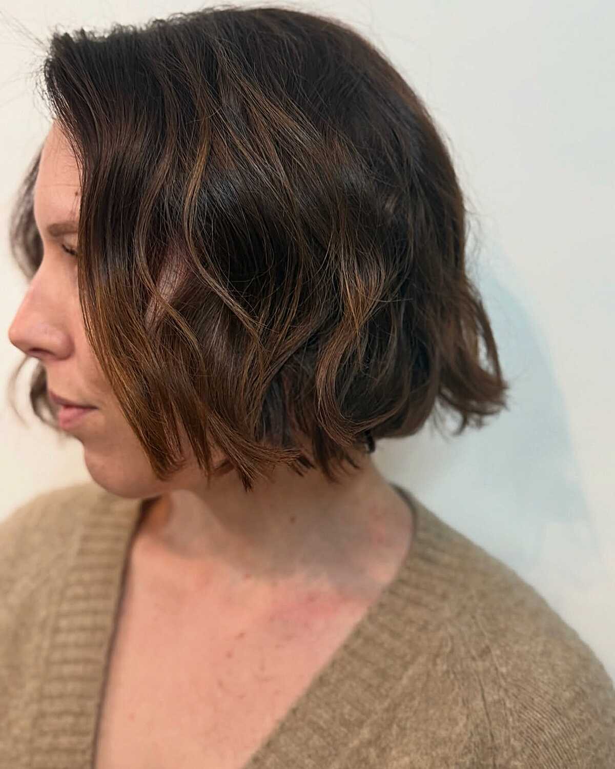 Short wavy dark brown bob with warm caramel highlights