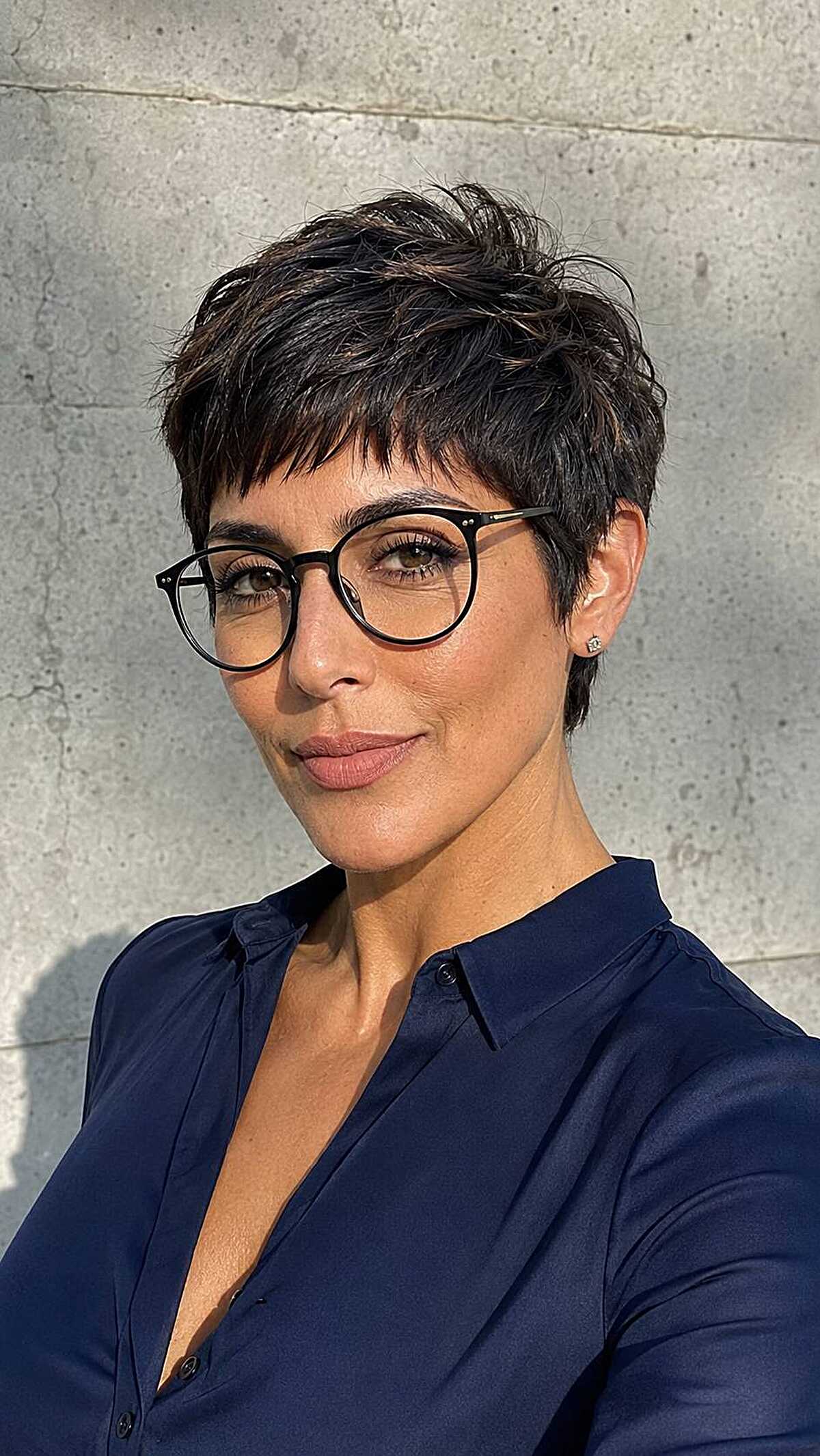 Short dark textured pixie with round black glasses