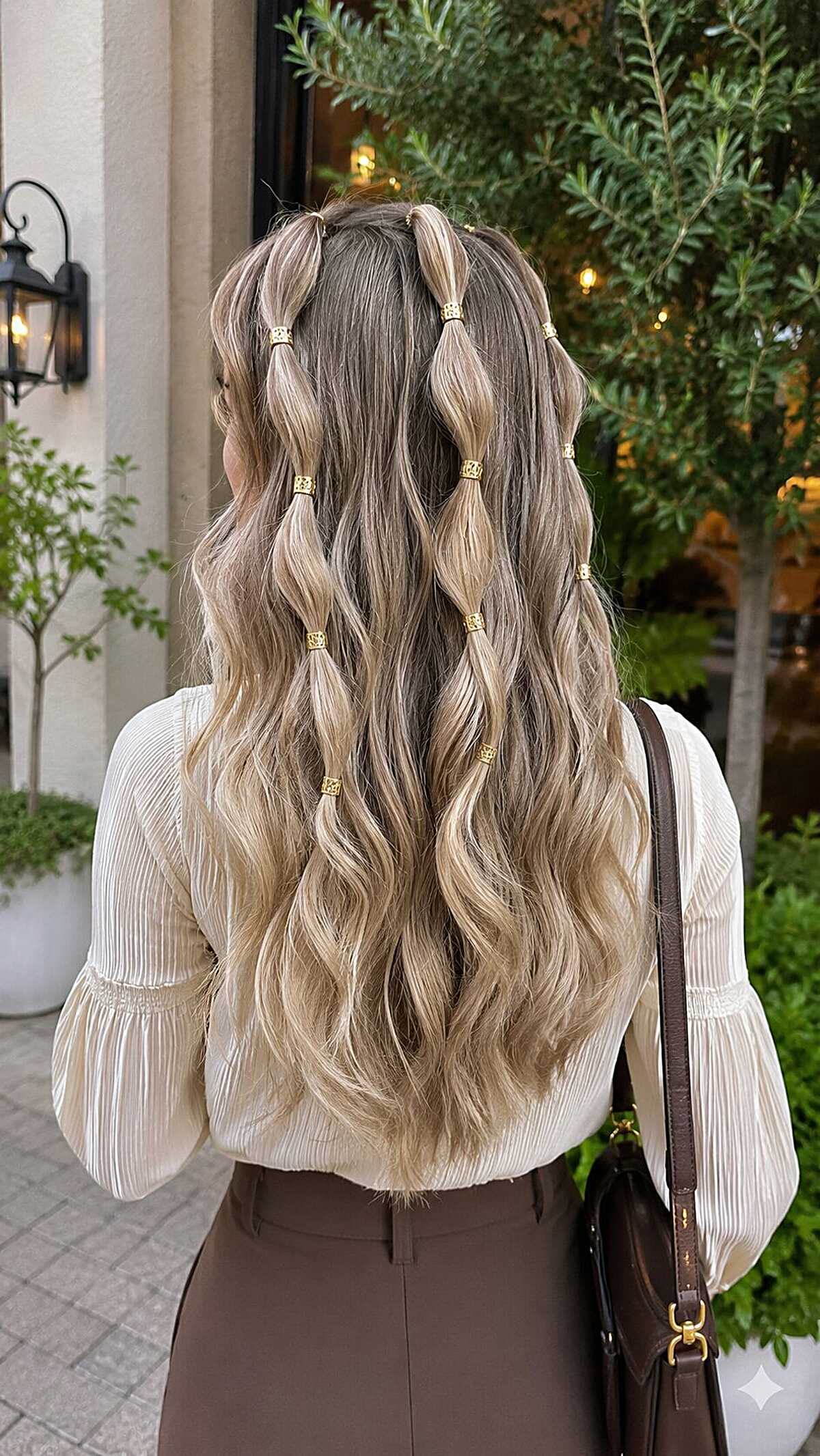 Half-down wavy hair with bubble braids and gold cuffs
