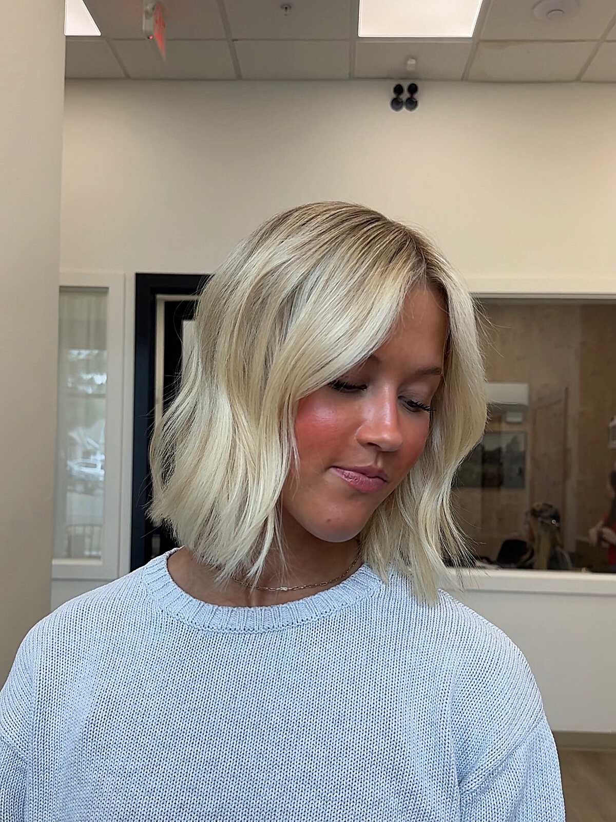 Platinum blonde wavy lob with dark roots and movement