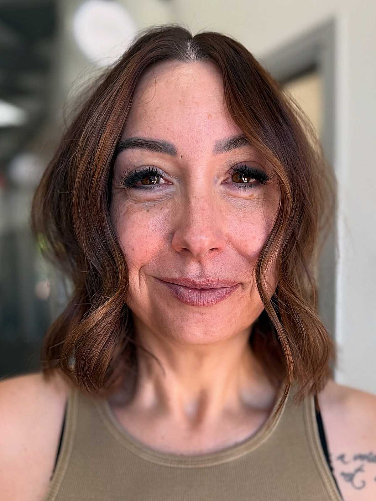 Warm cinnamon brown lob with soft face-framing waves