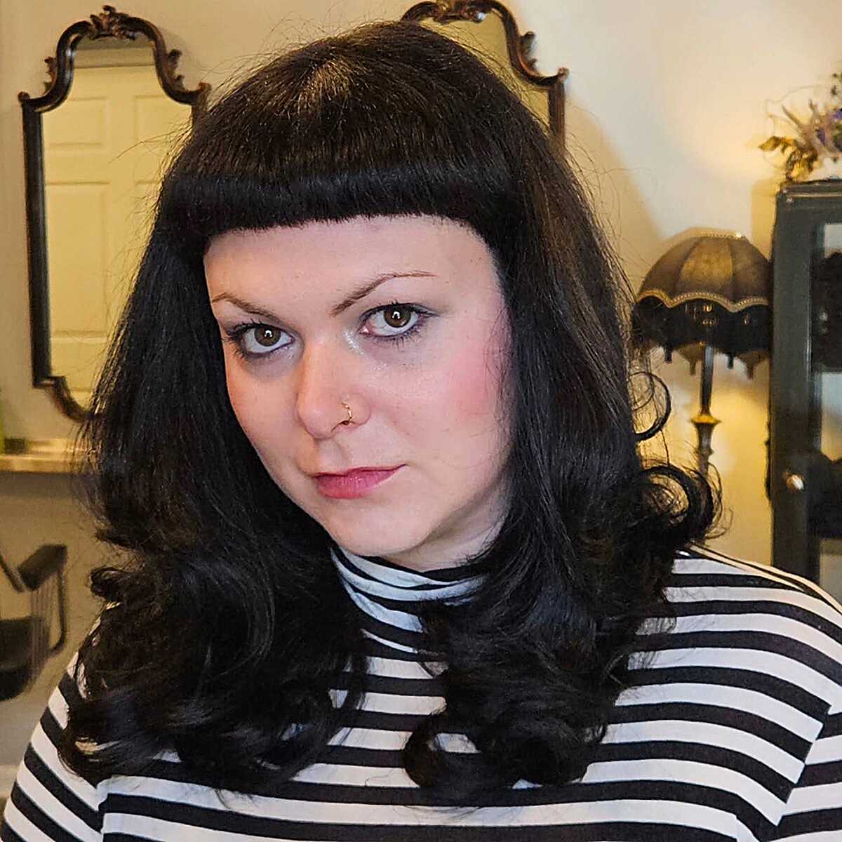 Dark wavy shoulder-length hair with arched micro bangs