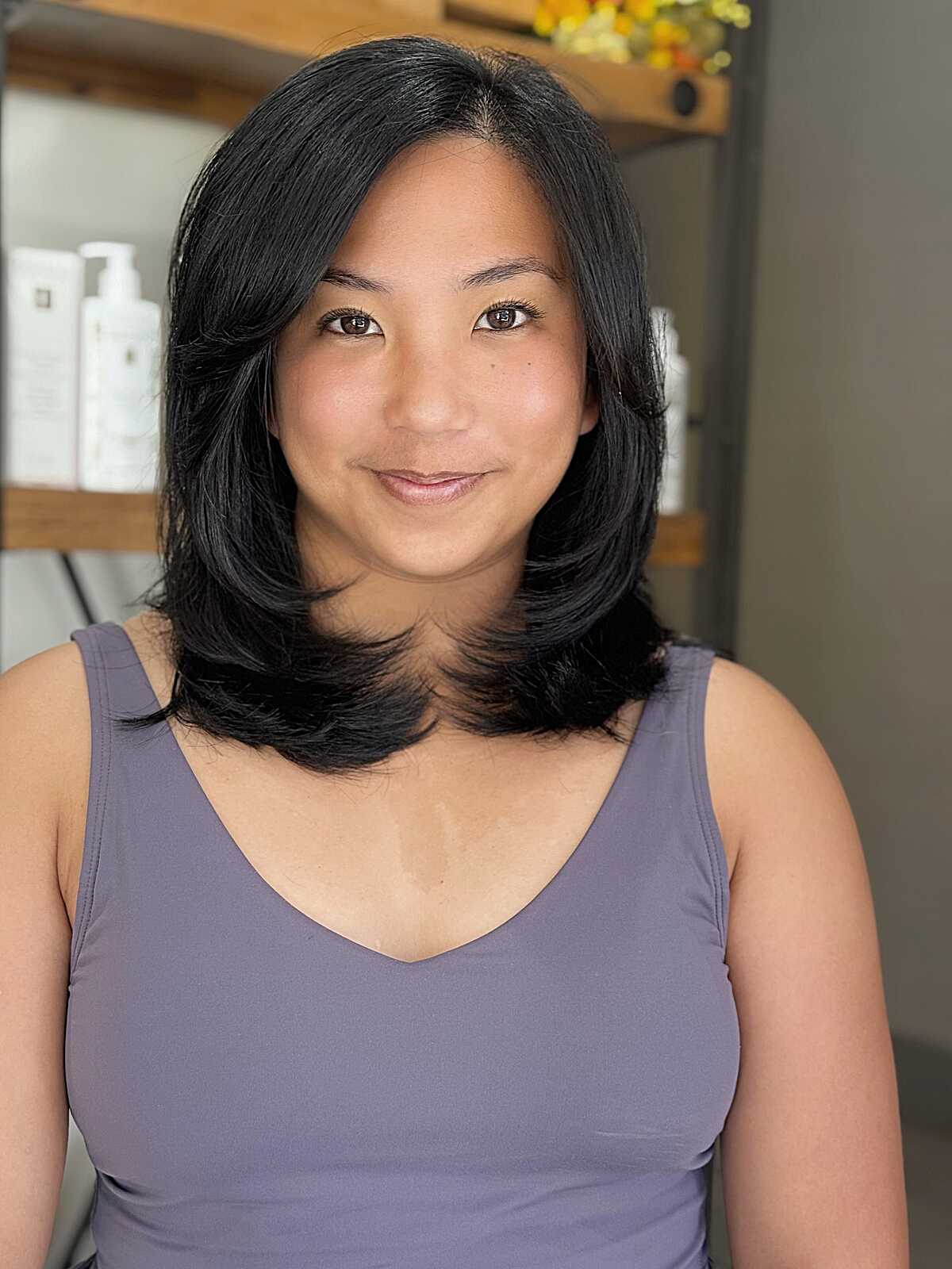 Black mid-length blowout lob with side part and volume