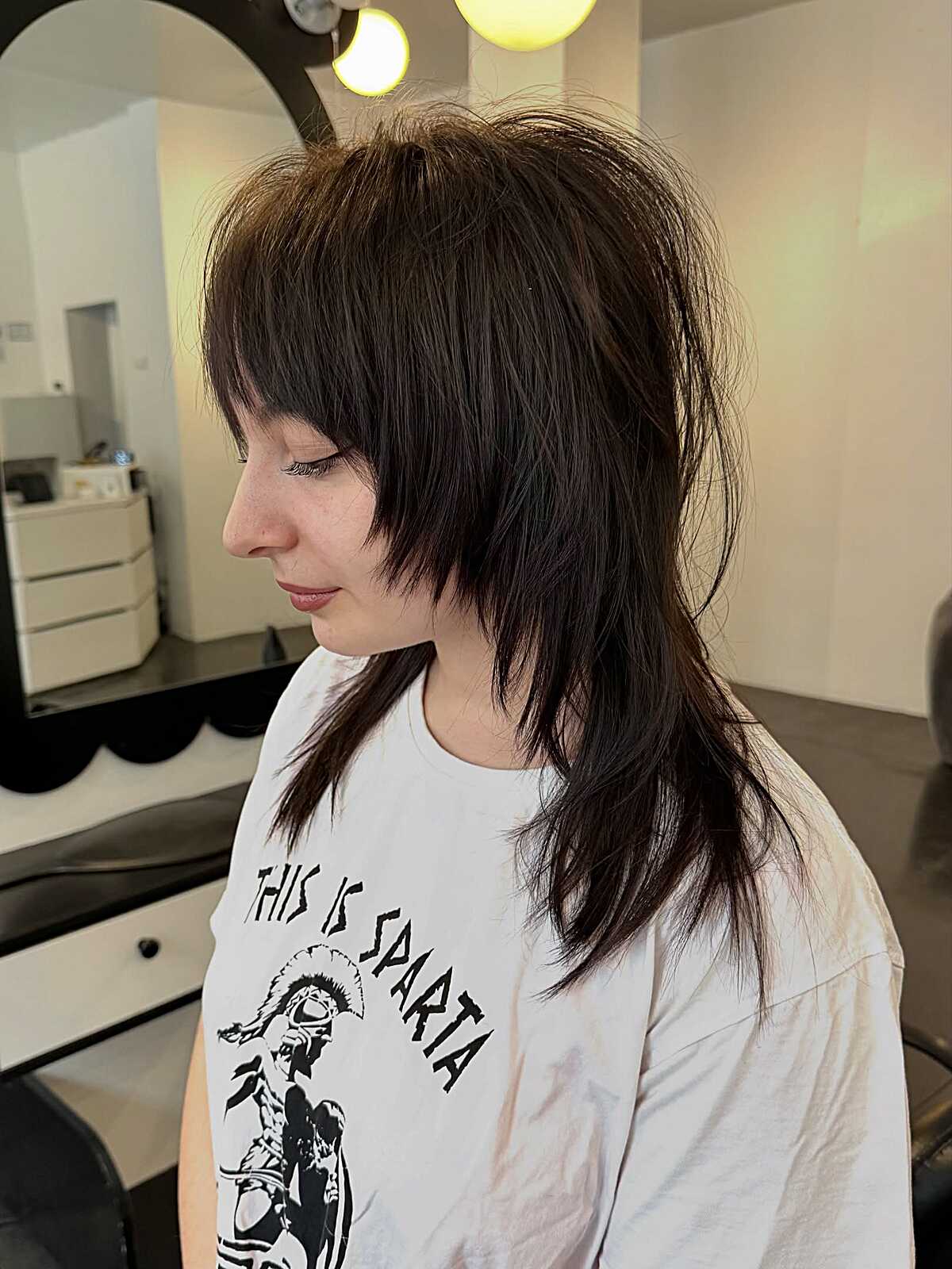 Dark brown choppy mid-length shag with heavy bangs