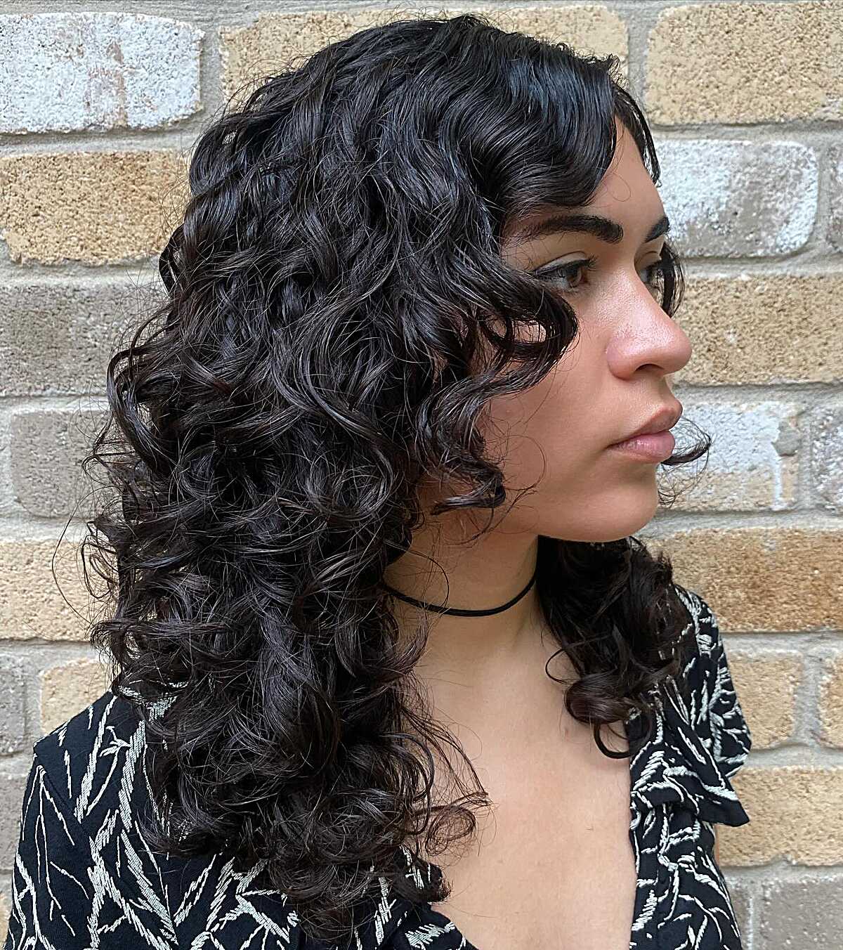 Black defined curly mid-length hair with side part