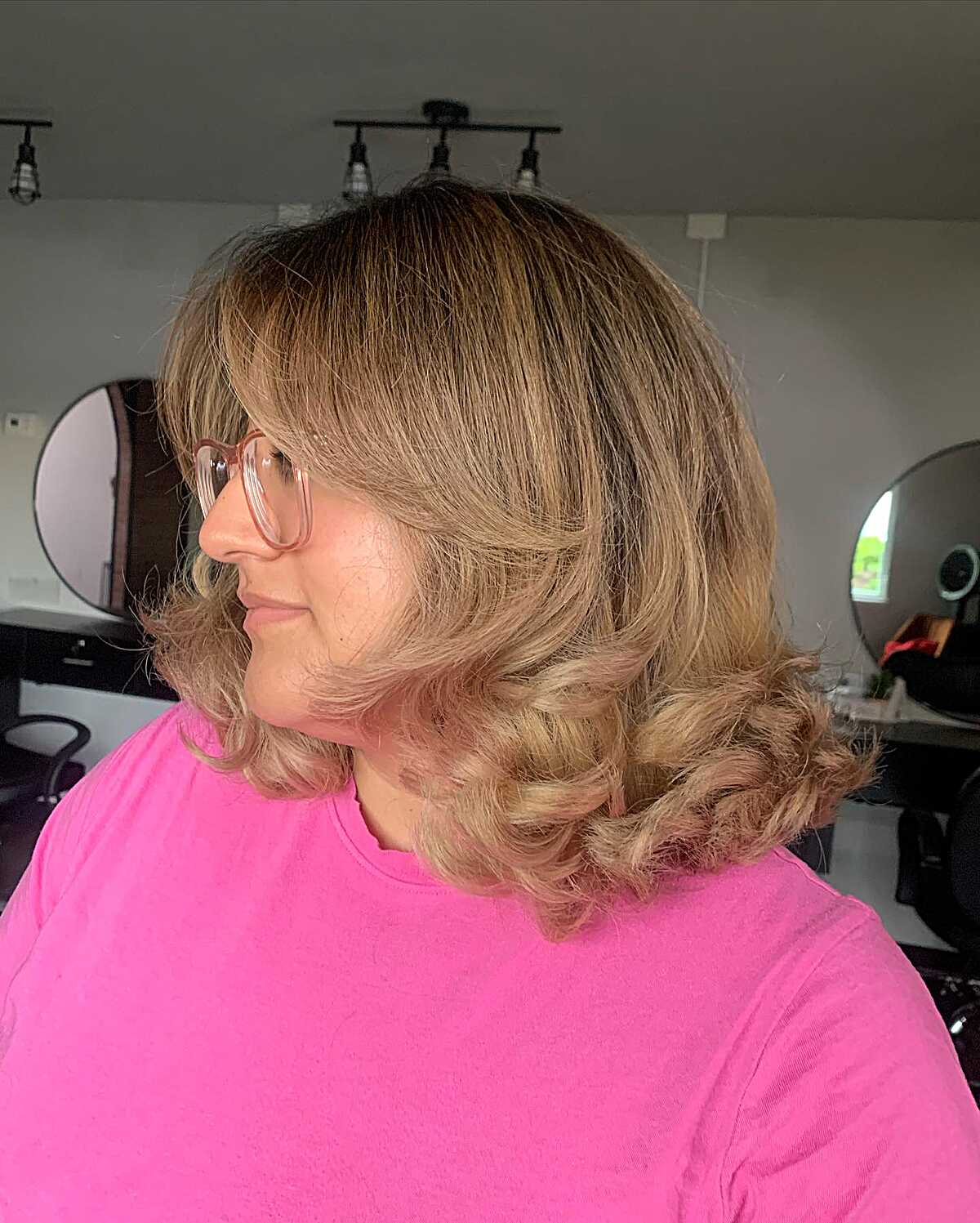 Honey blonde curly blowout with wispy bangs