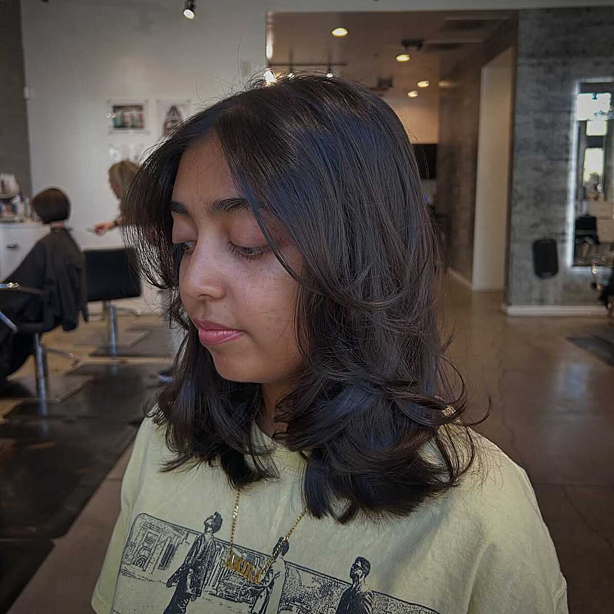 Dark mid-length layered blowout with side-swept fringe