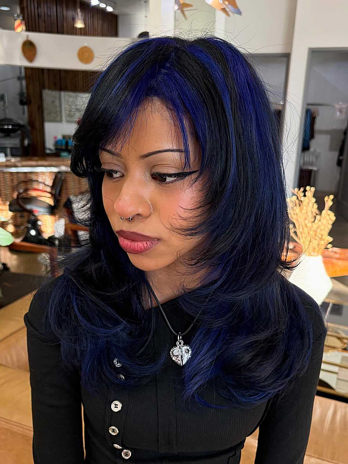Black wavy hair with deep blue highlights and side-swept bang