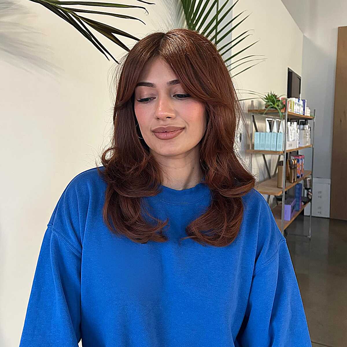 Warm auburn mid-length blowout with curtain bangs