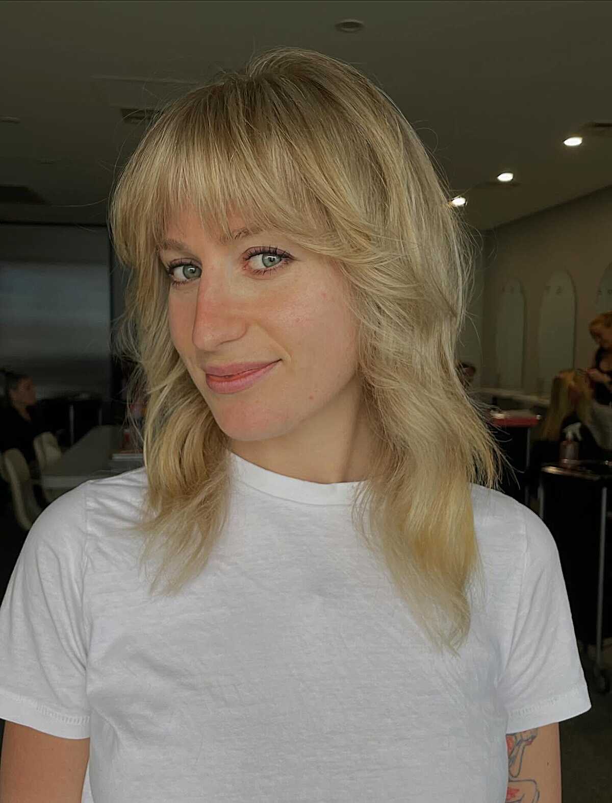 Warm blonde layered shag with full bangs and waves