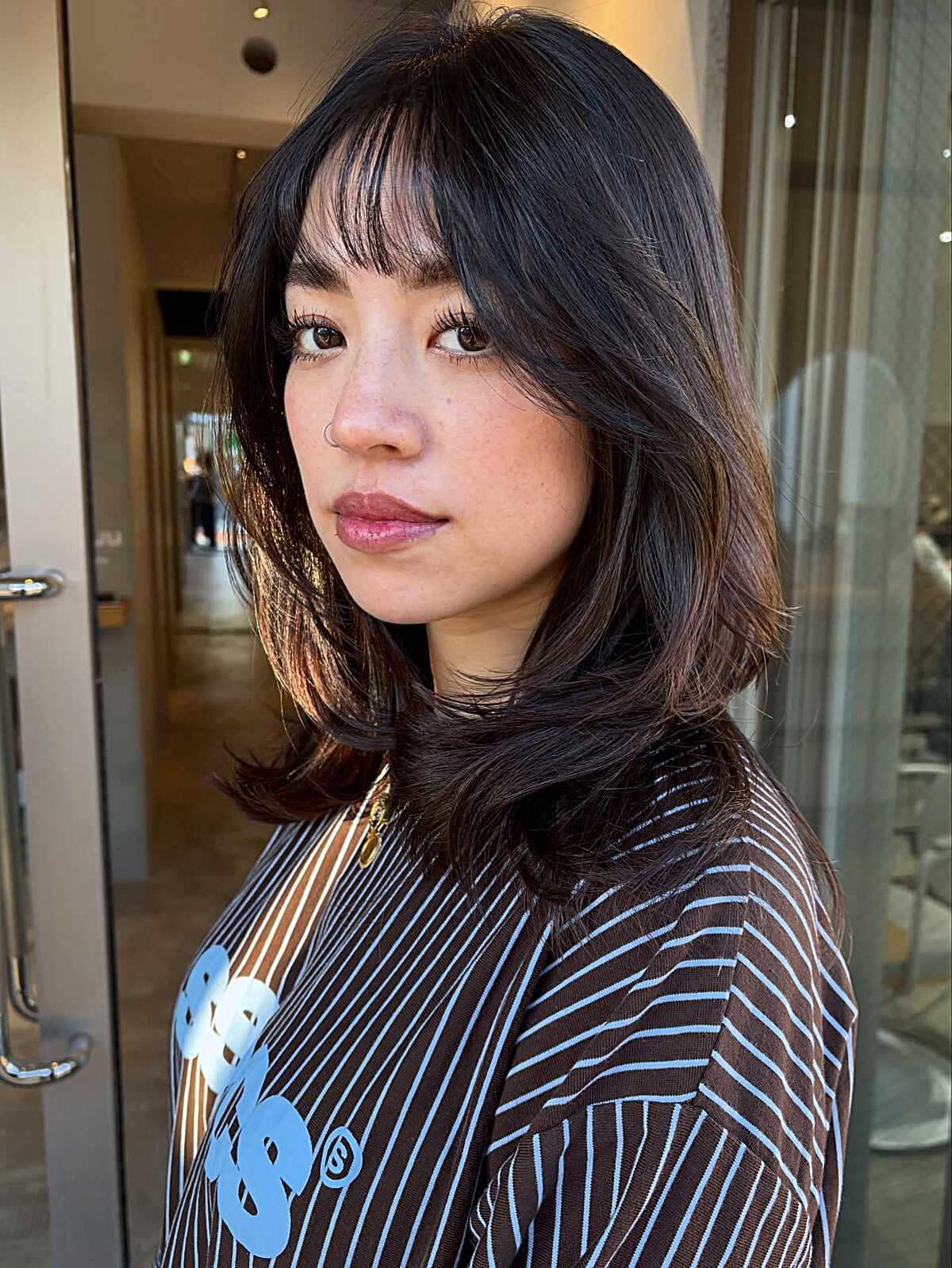 Dark brown wavy mid-length cut with wispy bangs