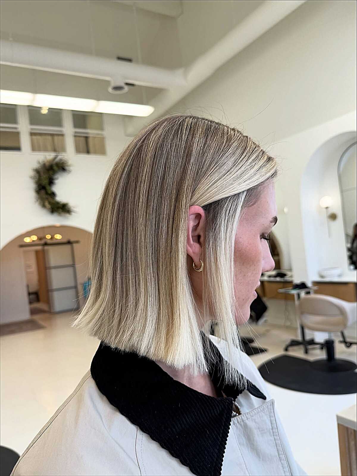 Sleek jaw-length blonde bob with subtle root shadow