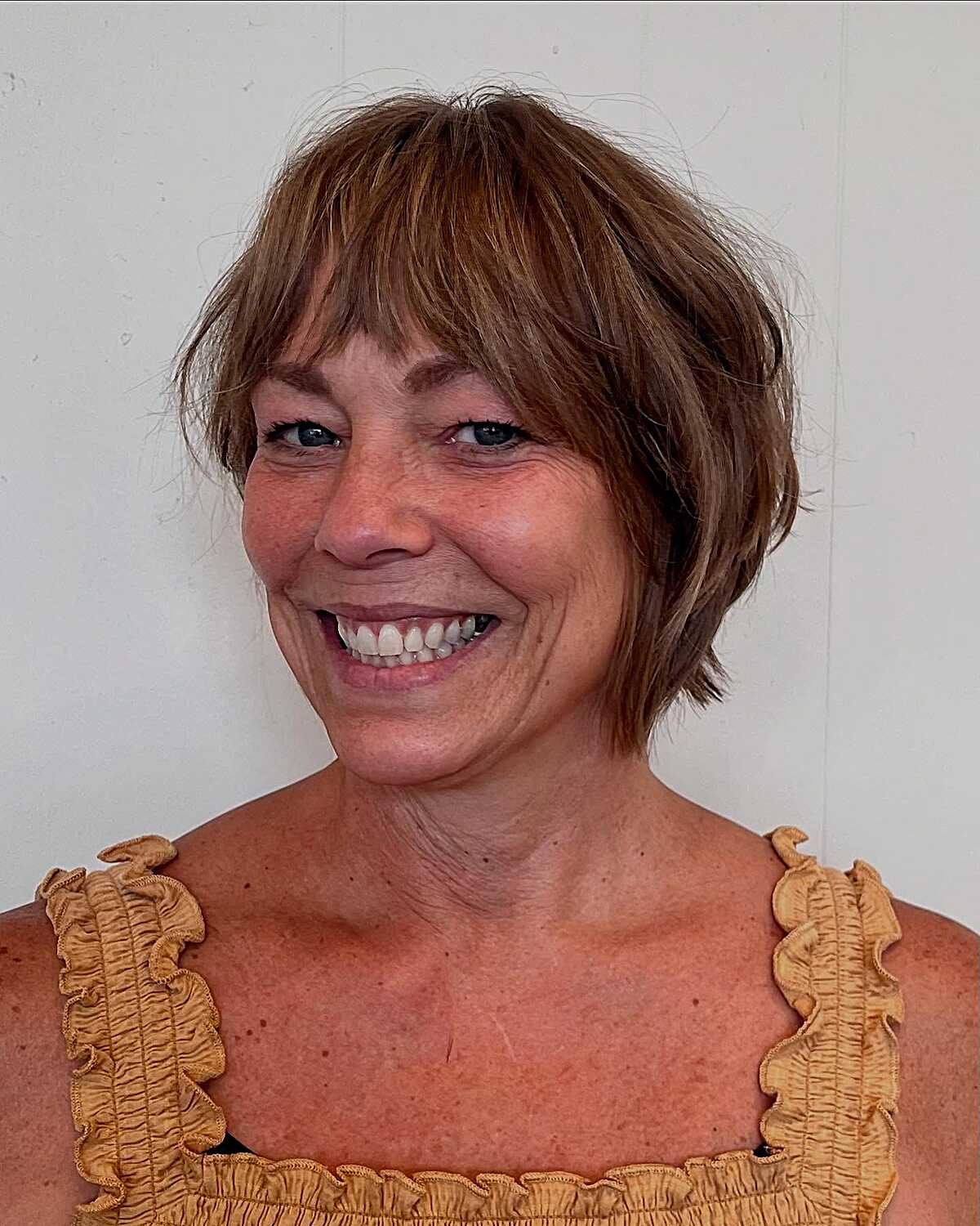 Copper brown shaggy bixie with bangs on smiling woman