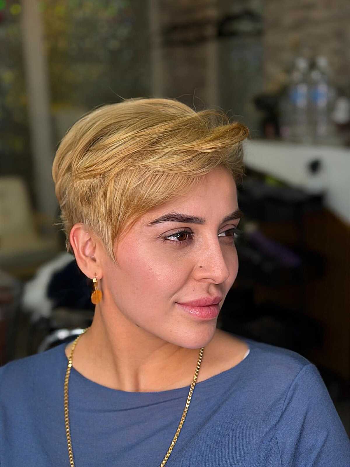 Golden blonde pixie cut swept back with short sides