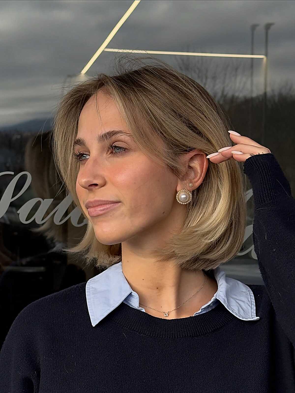 Short honey blonde bob tucked behind one ear