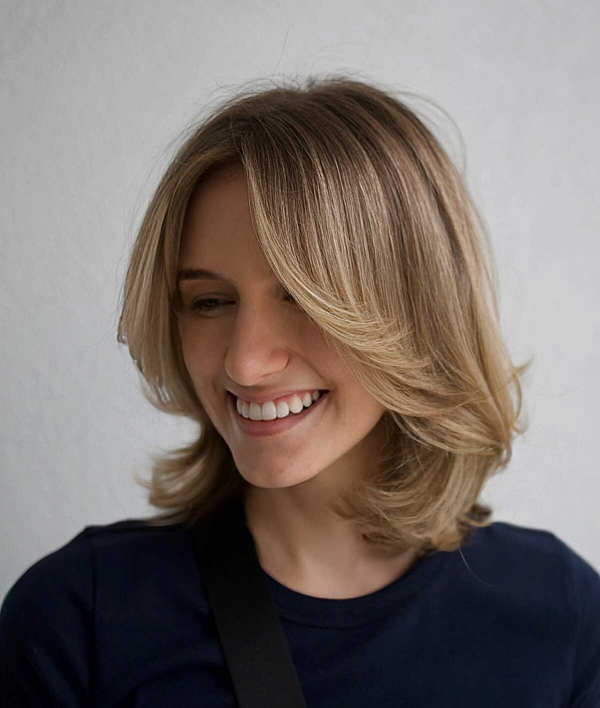Dirty blonde layered bob with flipped ends and side bang