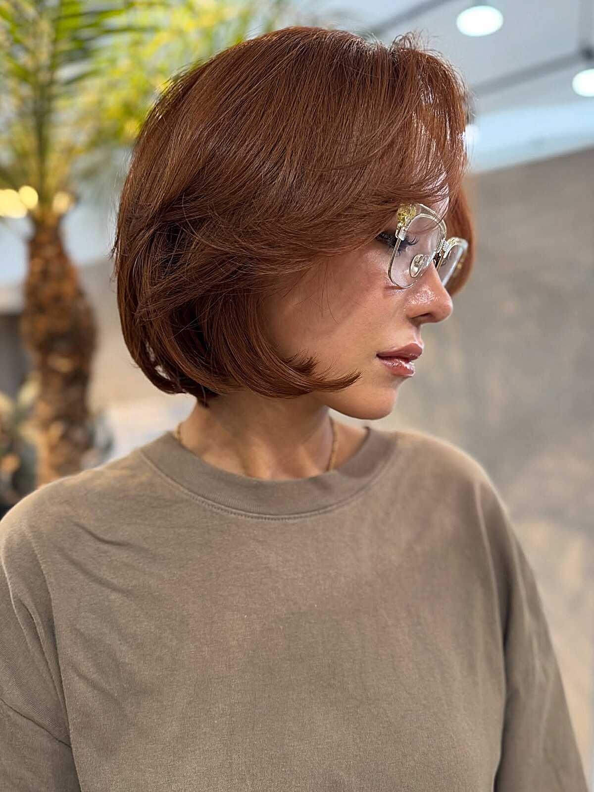 Short auburn layered bob with flipped styling and bangs