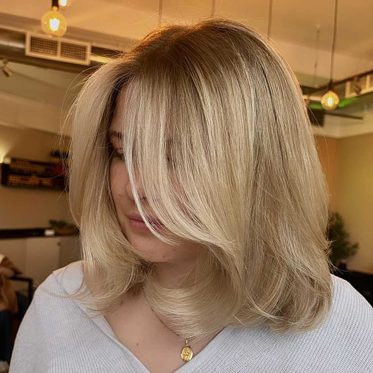 Warm blonde layered bob with curtain bangs and flipped ends