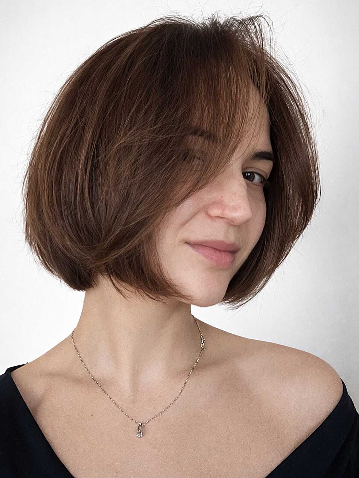 Short warm brunette bob with wispy side-swept bangs