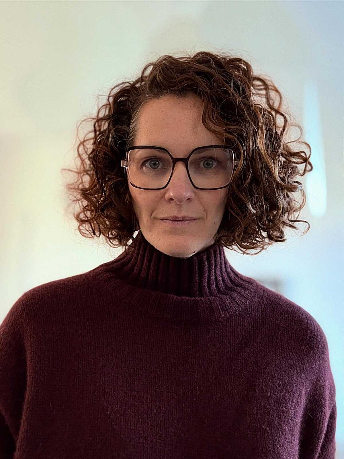 Chin-length dark brunette curly bob with glasses