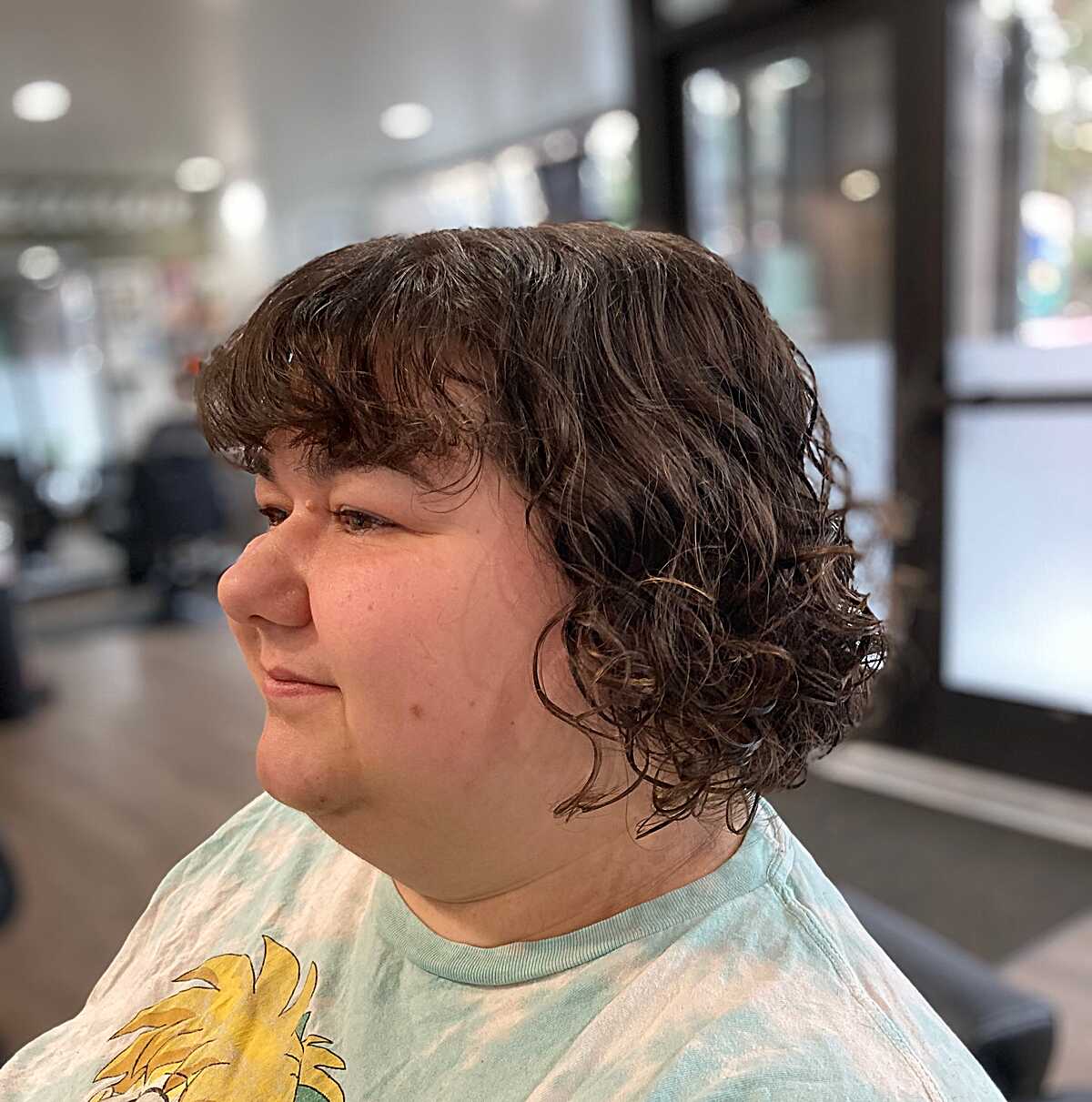 Brunette curly bob with soft bangs viewed from side