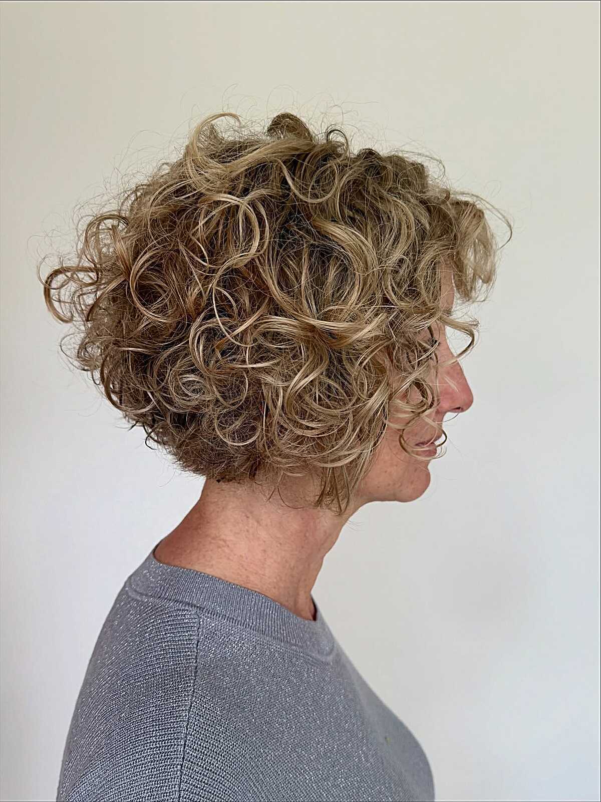 Side profile of short honey blonde curly bob with volume