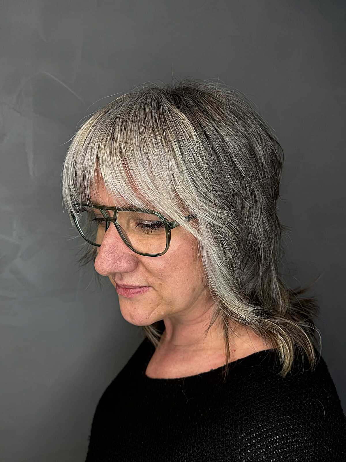 Salt and pepper shag with wispy bangs and glasses