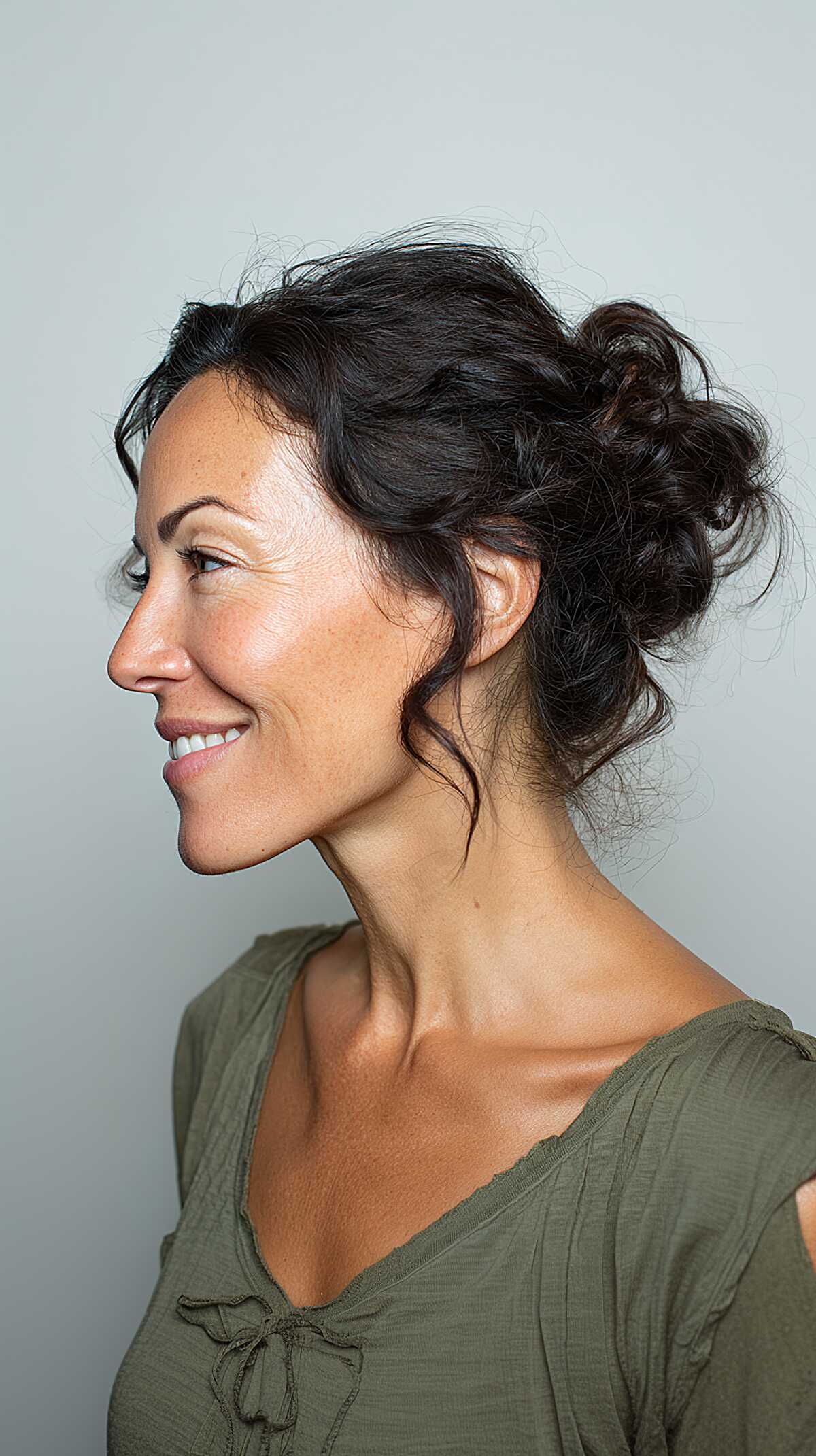 Low curly messy bun with romantic face-framing curls