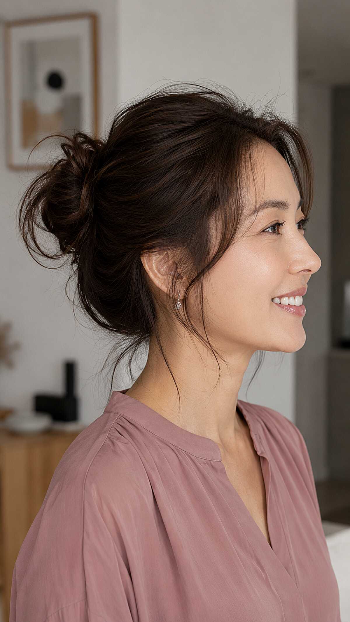 Dark low messy bun with delicate side-swept pieces