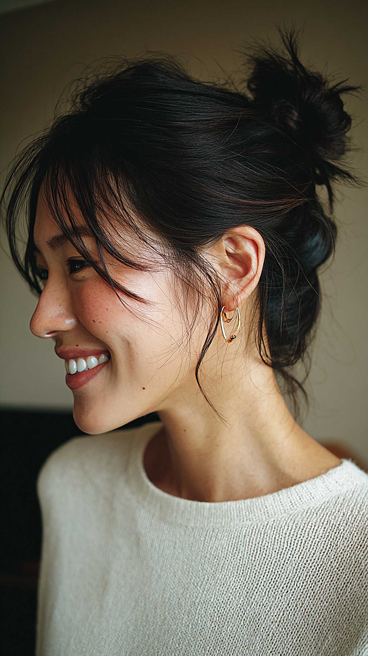 Jet black mini messy bun with wispy bangs
